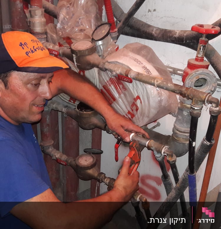 איש עם כובע עובד על צינורות ומד לחץ